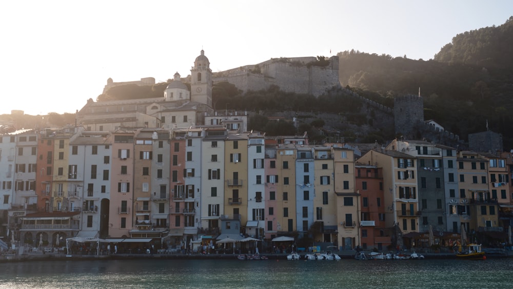 a group of buildings sitting on top of a hill next to a body of water