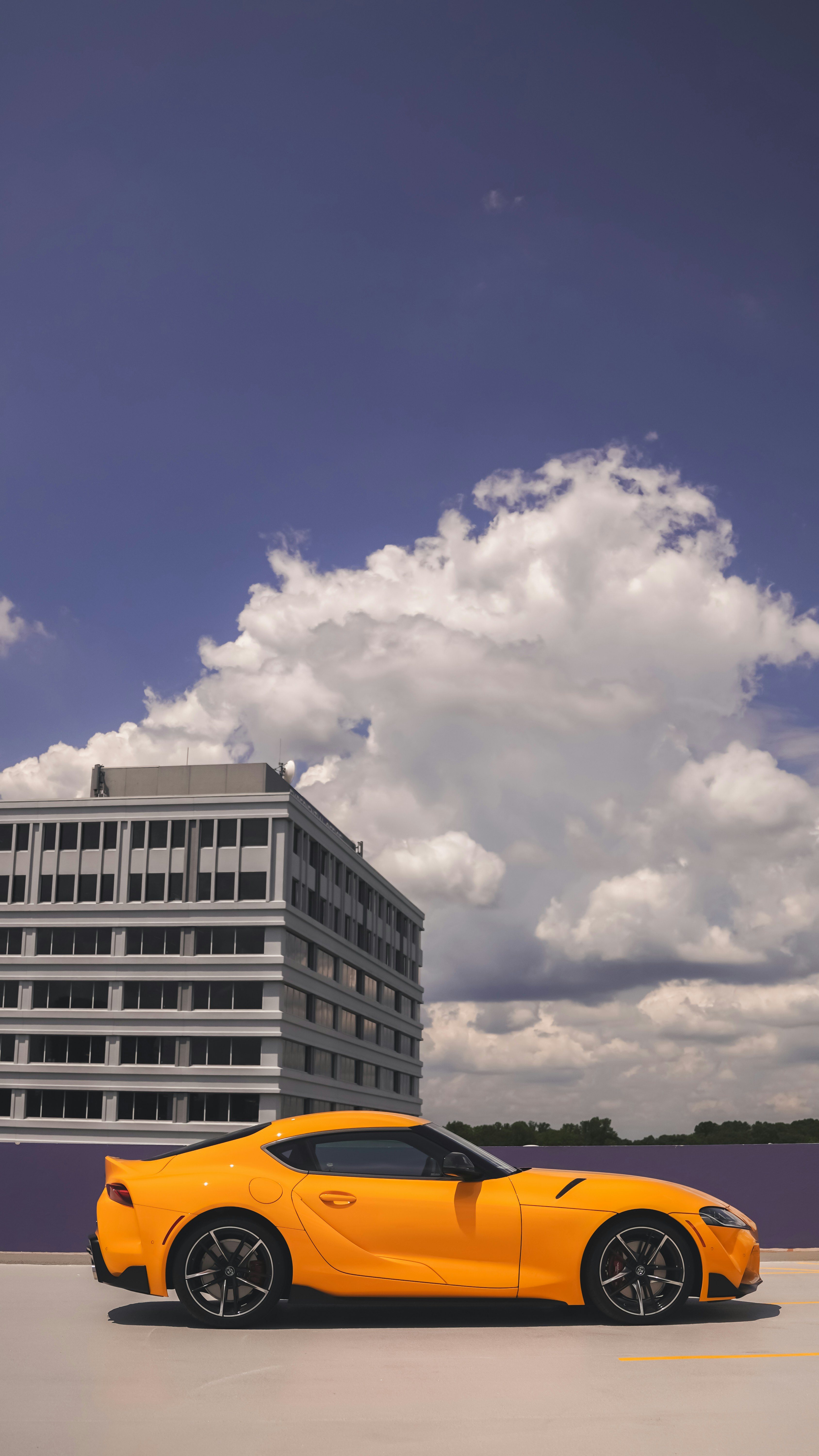 A yellow sports car parked in front of a tall building