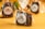 Individually wrapped chocolate brownies are neatly packaged in transparent plastic with an orange ribbon, placed against a warm yellow background. The brand label, featuring a stylized logo and text, is visible on the packaging.