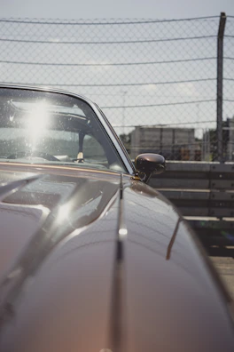 Close-up of a freshly sandblasted vintage car hood gleaming under sunlight.