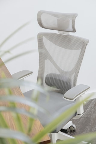 a white ergonomic chair sitting next to a wooden desk