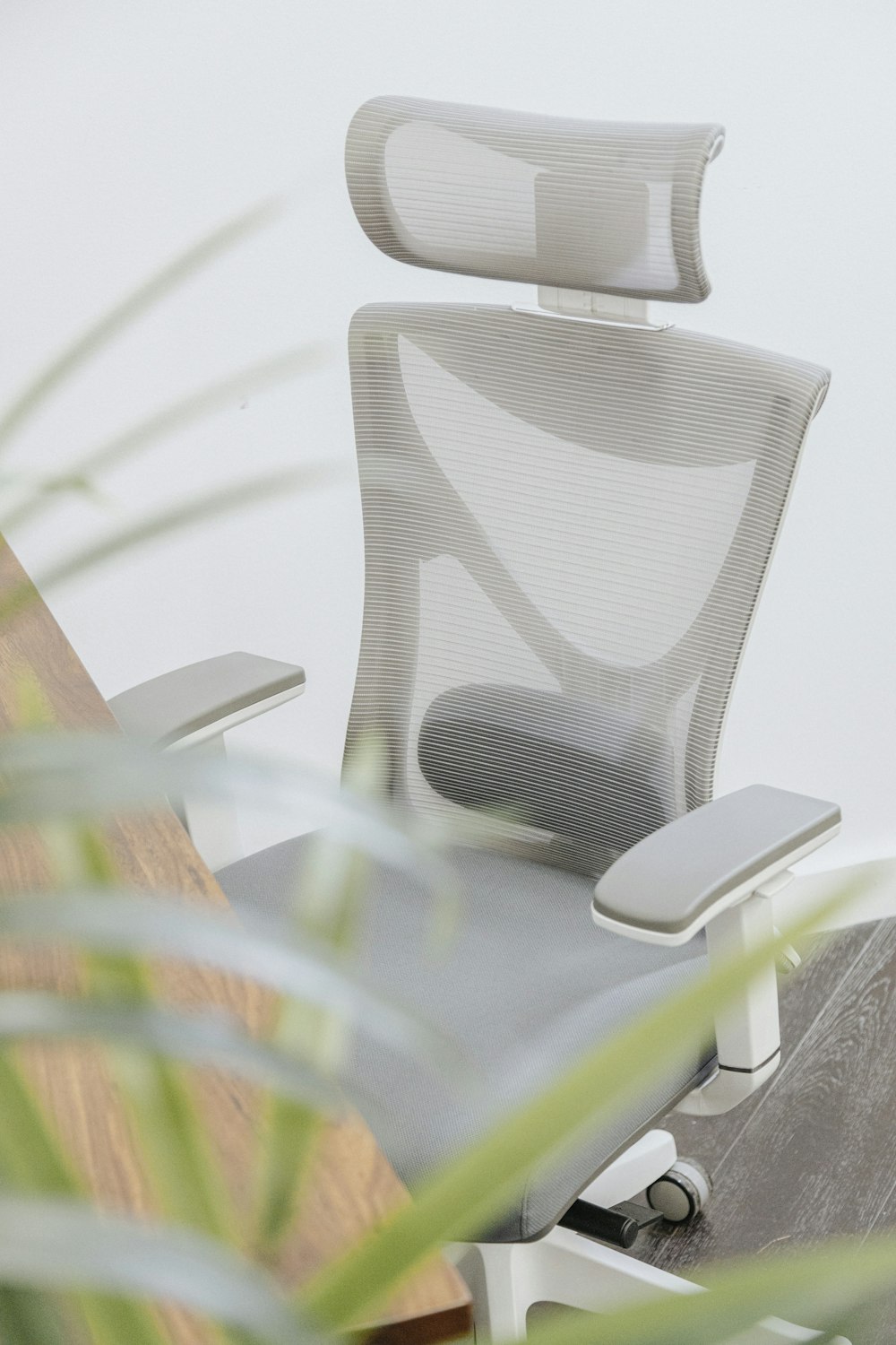 Una silla de oficina blanca sentada encima de un escritorio de madera