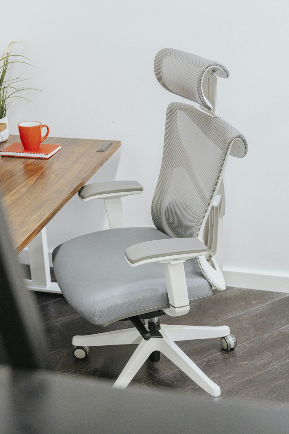 Una silla de oficina gris sentada junto a una mesa de madera