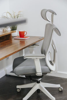 Adjustable metal footrest with cushioned top in a bright office space.