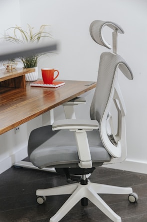 A cozy gray fabric swivel chair positioned beside a wooden desk with office supplies.