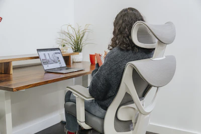 Person seated in Flexispot ergonomic mesh office chair at desk with laptop