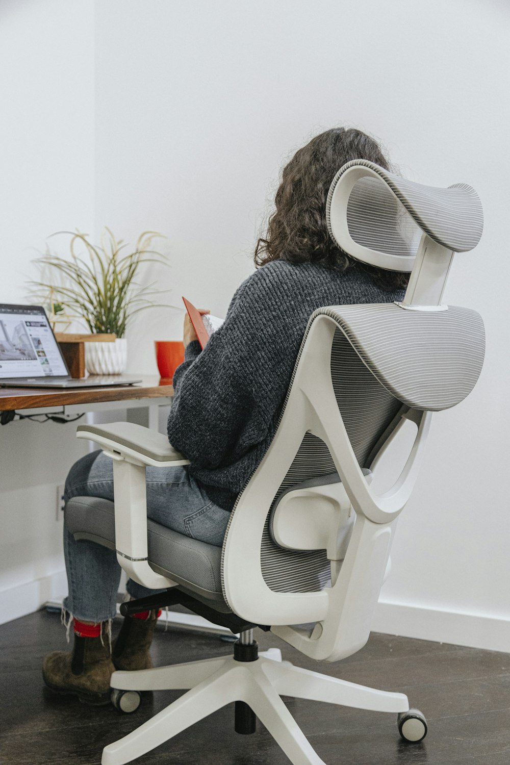 a woman sitting in an office chair with a computer on her desk