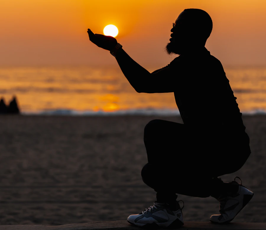A man sitting on the sand as the sun goes down