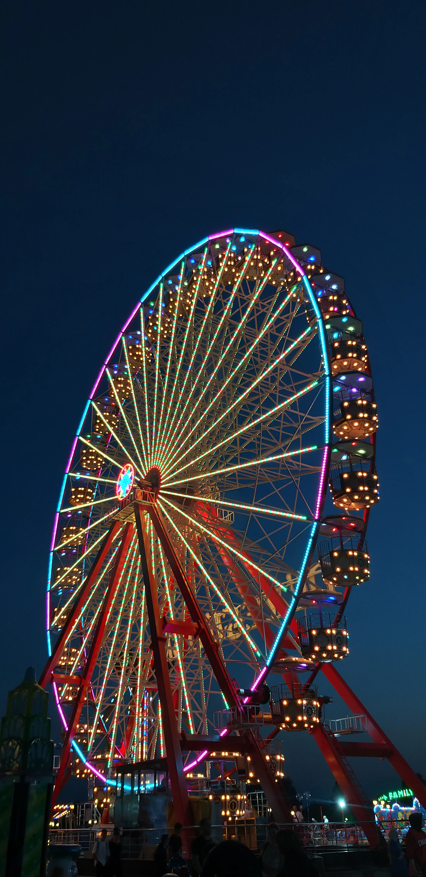 Noria iluminada al anochecer en un parque de atracciones