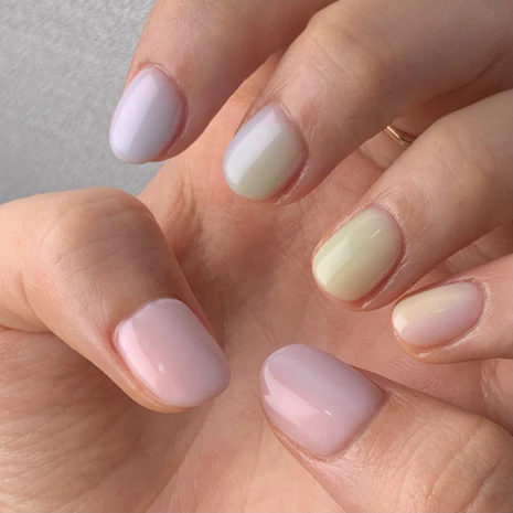 Close-up of perfectly manicured hands showcasing a minimalist gel-x nail design in pastel tones.