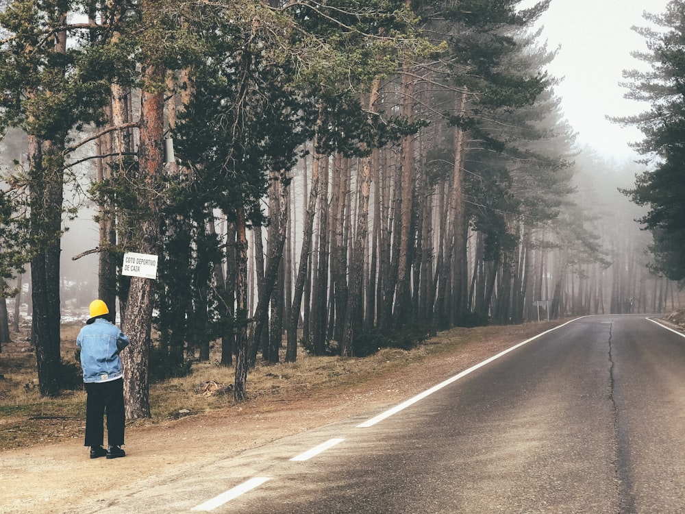 a person standing on the side of a road holding a sign