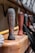 Wooden handles with a weathered texture lined up on a wooden surface, accompanied by coiled black ropes and hardware components in a blurred background.