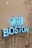A vibrant blue neon sign reads 'HELLO BOSTON' mounted on a wall with white subway tiles and black line art illustrations depicting cityscapes and various designs.