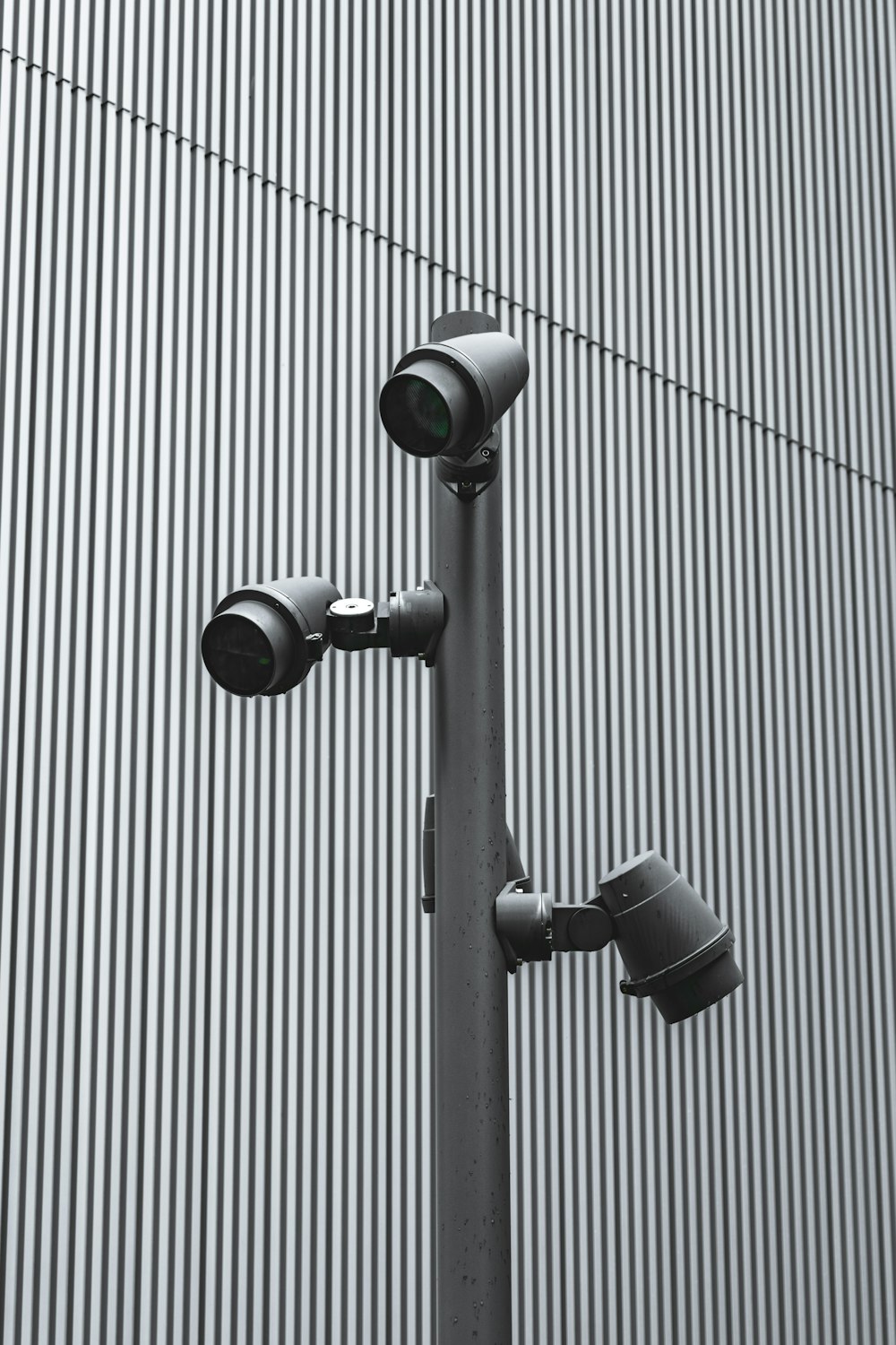 three cameras on a pole in front of a building