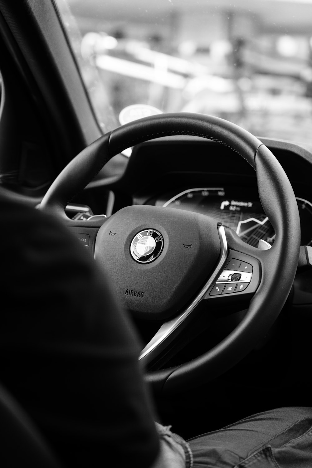 a black and white photo of a man driving a car