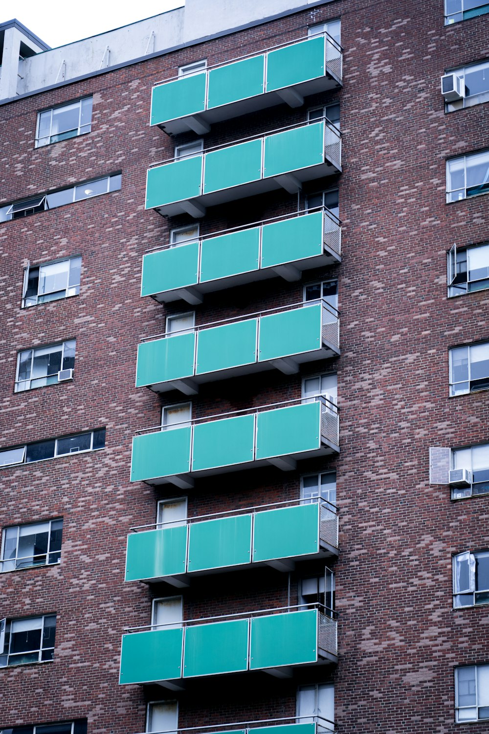 a tall brick building with balconies and green balconies
