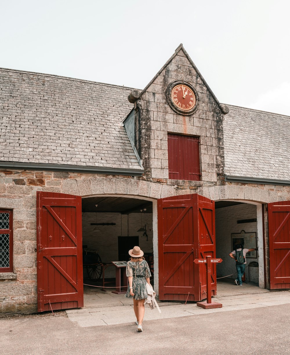 a woman in a hat walks past a building with red shutters