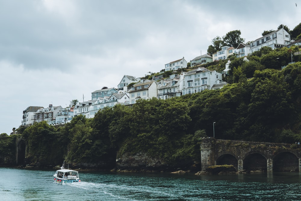 a boat traveling down a river next to a lush green hillside