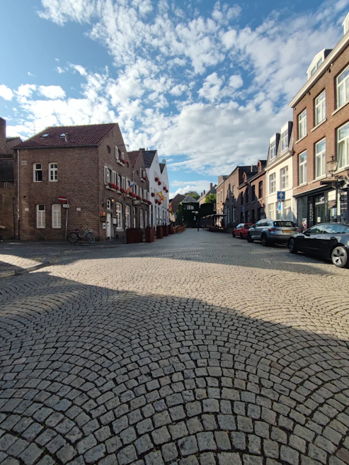 Cobblestone street in Prague lined with colorful historic buildings under a bright blue sky