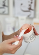 a woman is holding a jar of lip balm