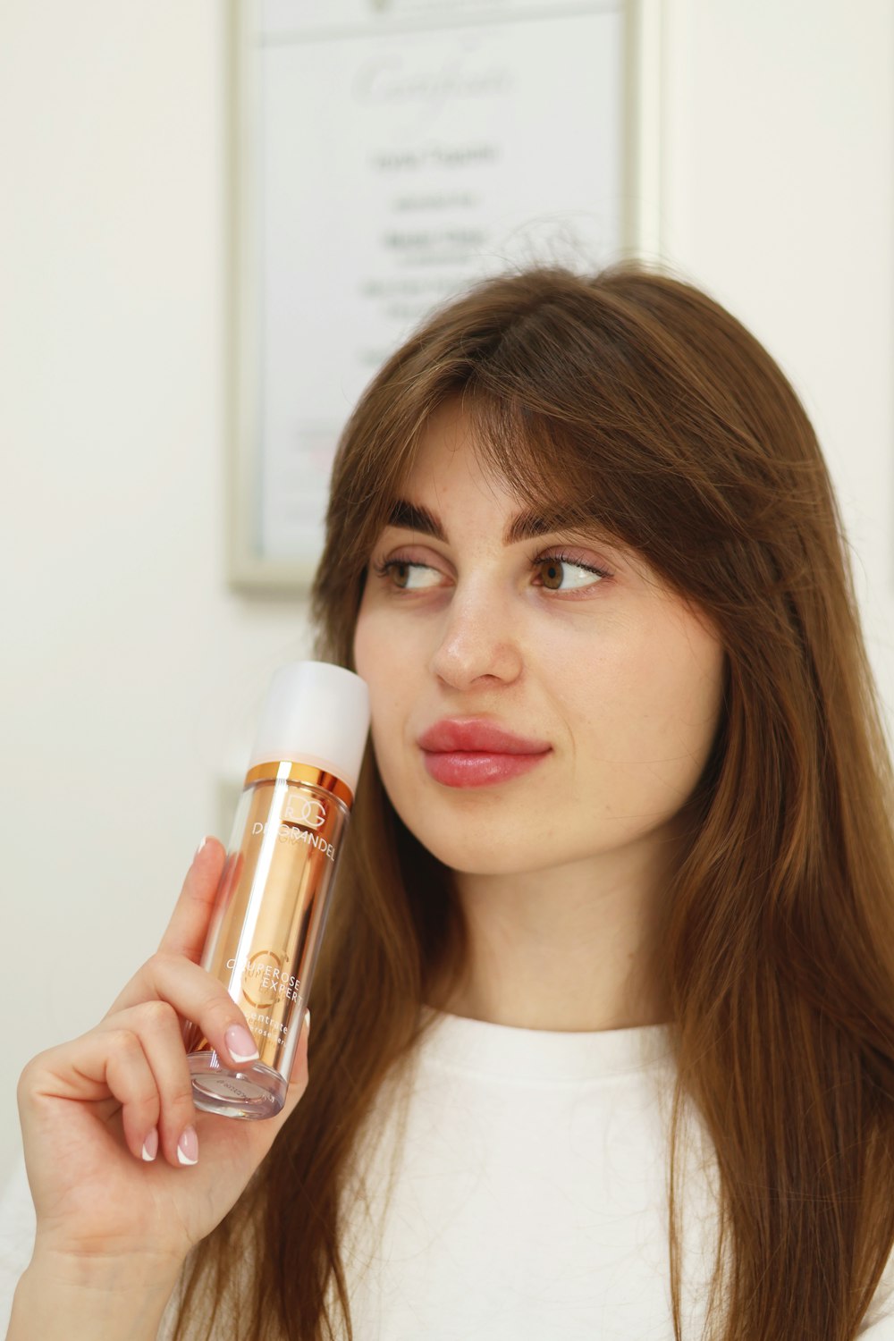 a woman is holding a bottle of makeup