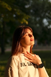 a woman standing in a park with her hands on her chest