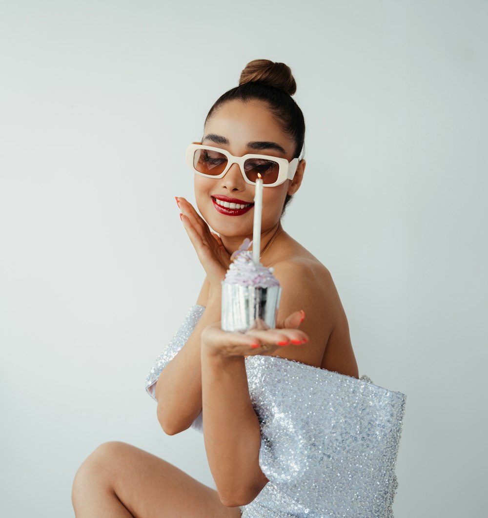 a woman in a white dress holding a cupcake