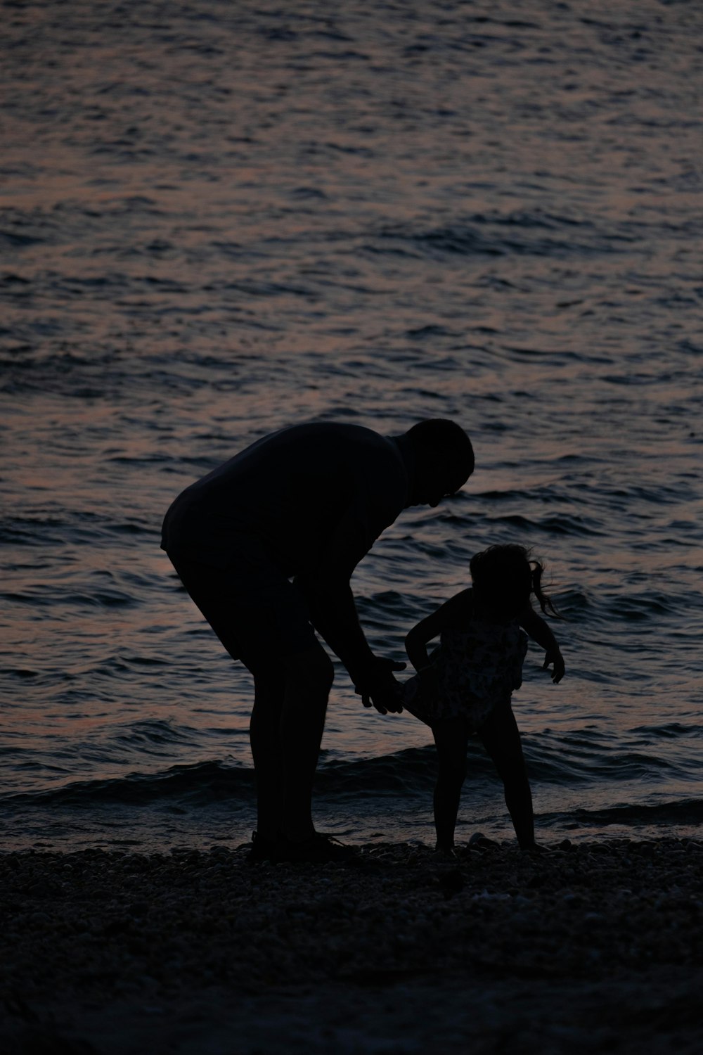 Un uomo che tiene la mano di una bambina sulla spiaggia