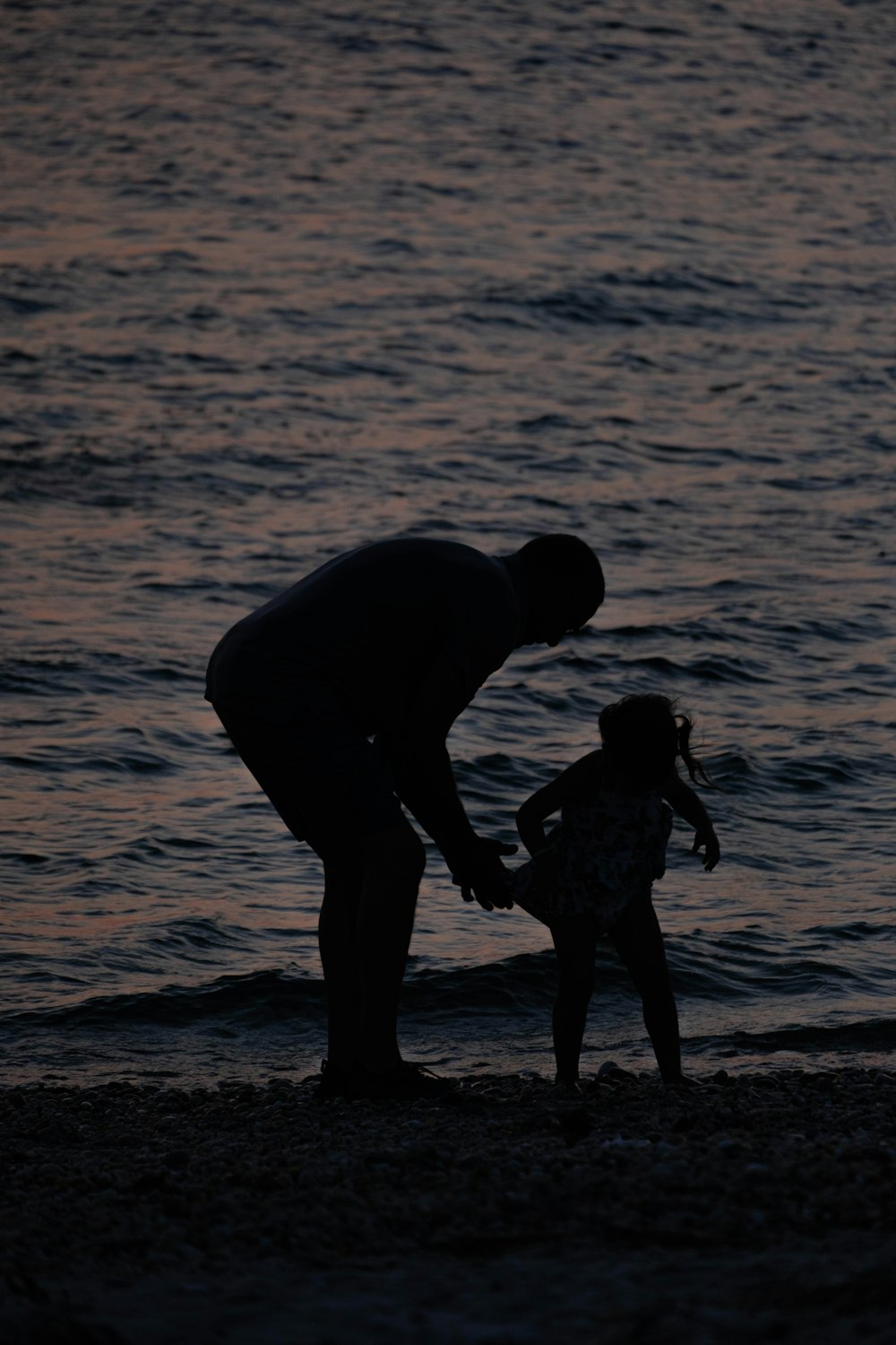 a man holding a little girl's hand on the beach