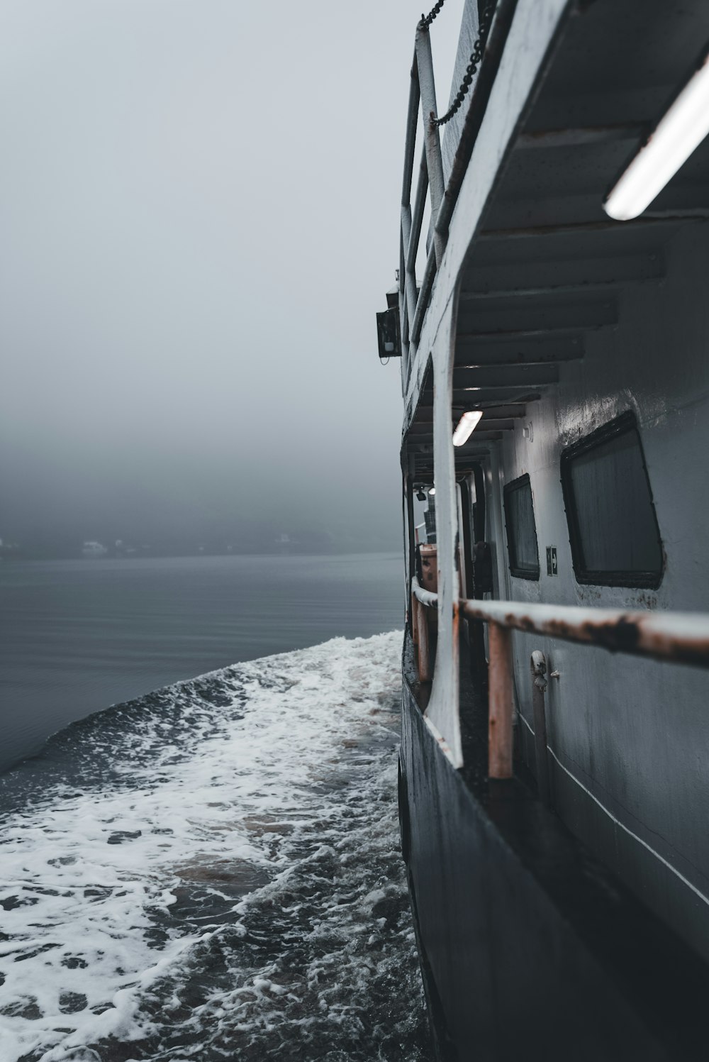 a boat traveling through the ocean on a foggy day