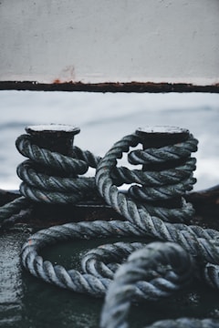 Workers securing cargo with lashing ropes on a ship deck.