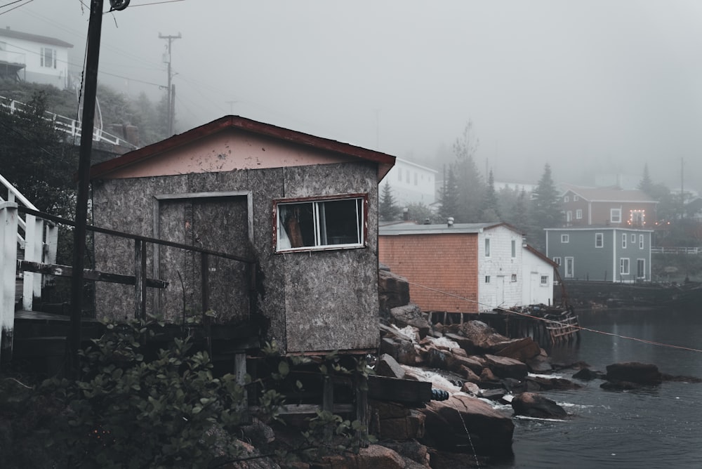 a small house sitting on the shore of a body of water