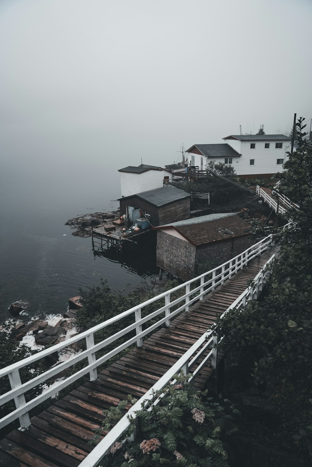 a foggy day at a dock with a house on the water