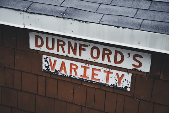 The image features a weathered sign on a wooden structure with the words 'DURNFORD'S VARIETY' in bold red letters against a white background. The roof is covered in dark gray shingles.