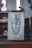 A podium with a hanging cloth featuring a religious symbol made up of a cross, the Greek letters Alpha and Omega, and a laurel wreath. A microphone is positioned next to the podium. The setting is likely within a church, indicated by the dimly lit interior and stained glass decor in the background.