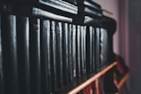 A row of dark, leather-bound books neatly lined up on a wooden shelf. The books exhibit a classic and aged appearance, suggesting they may contain collections of literature or encyclopedias. The lighting is dim, creating a moody atmosphere.