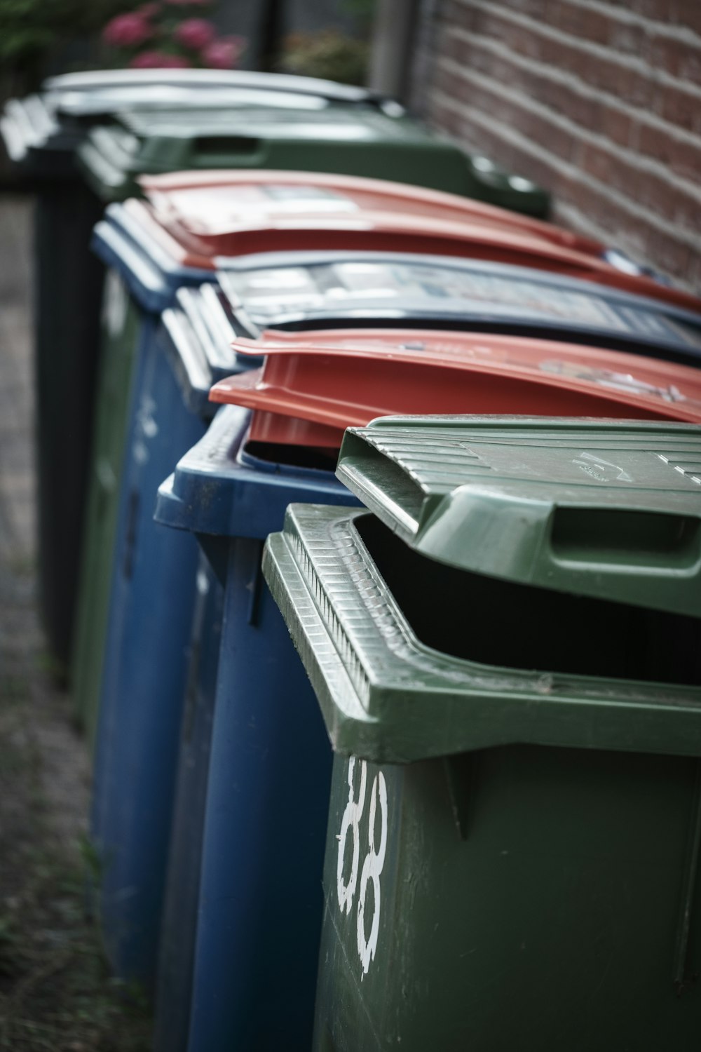 a row of trash cans sitting next to a brick wall