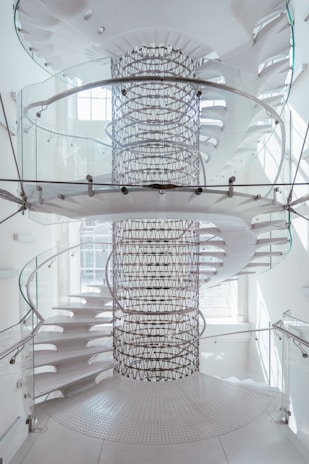 a spiral staircase in a white building with glass railings