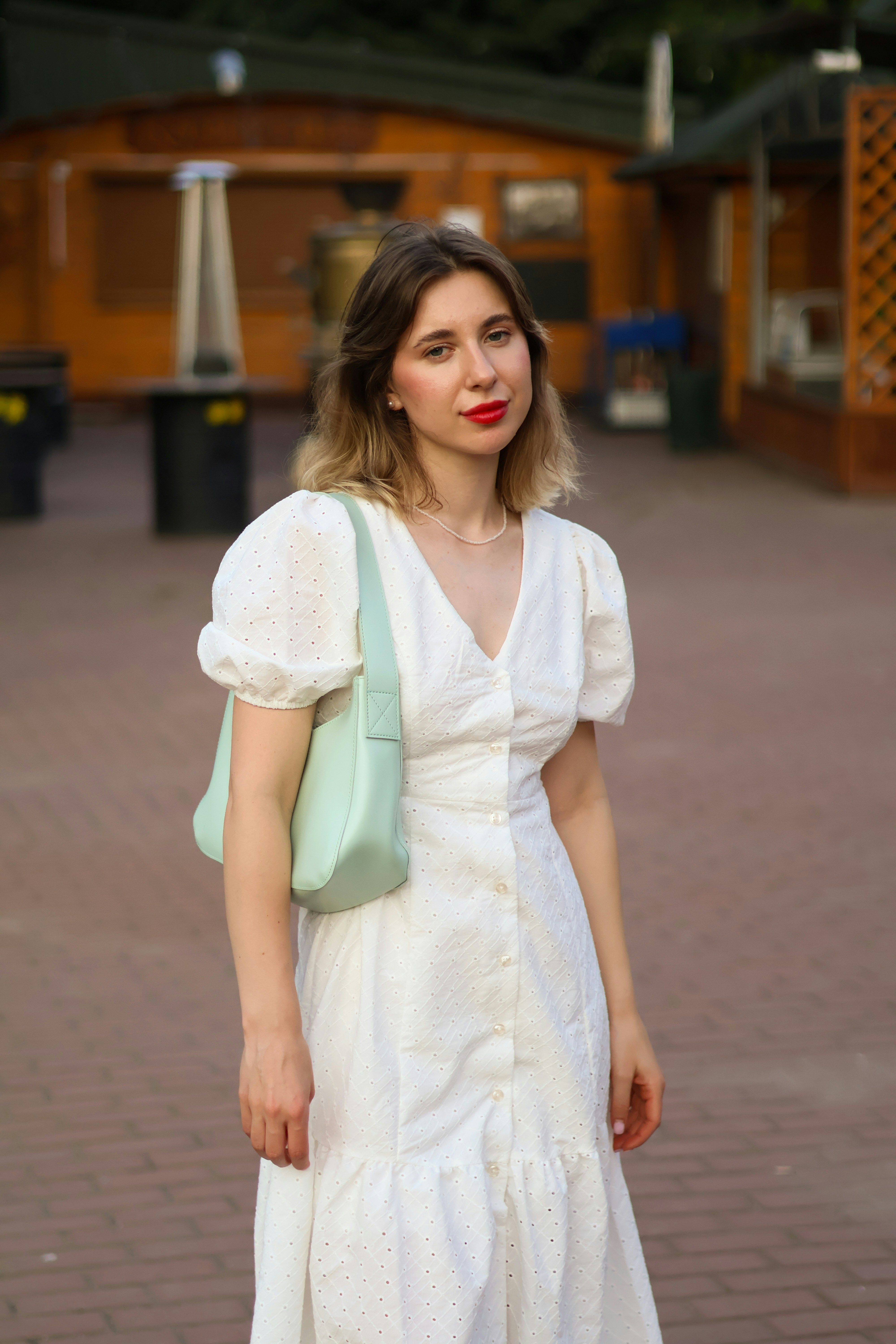 a woman in a white dress with a green purse