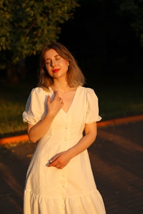 a woman in a white dress standing on a sidewalk