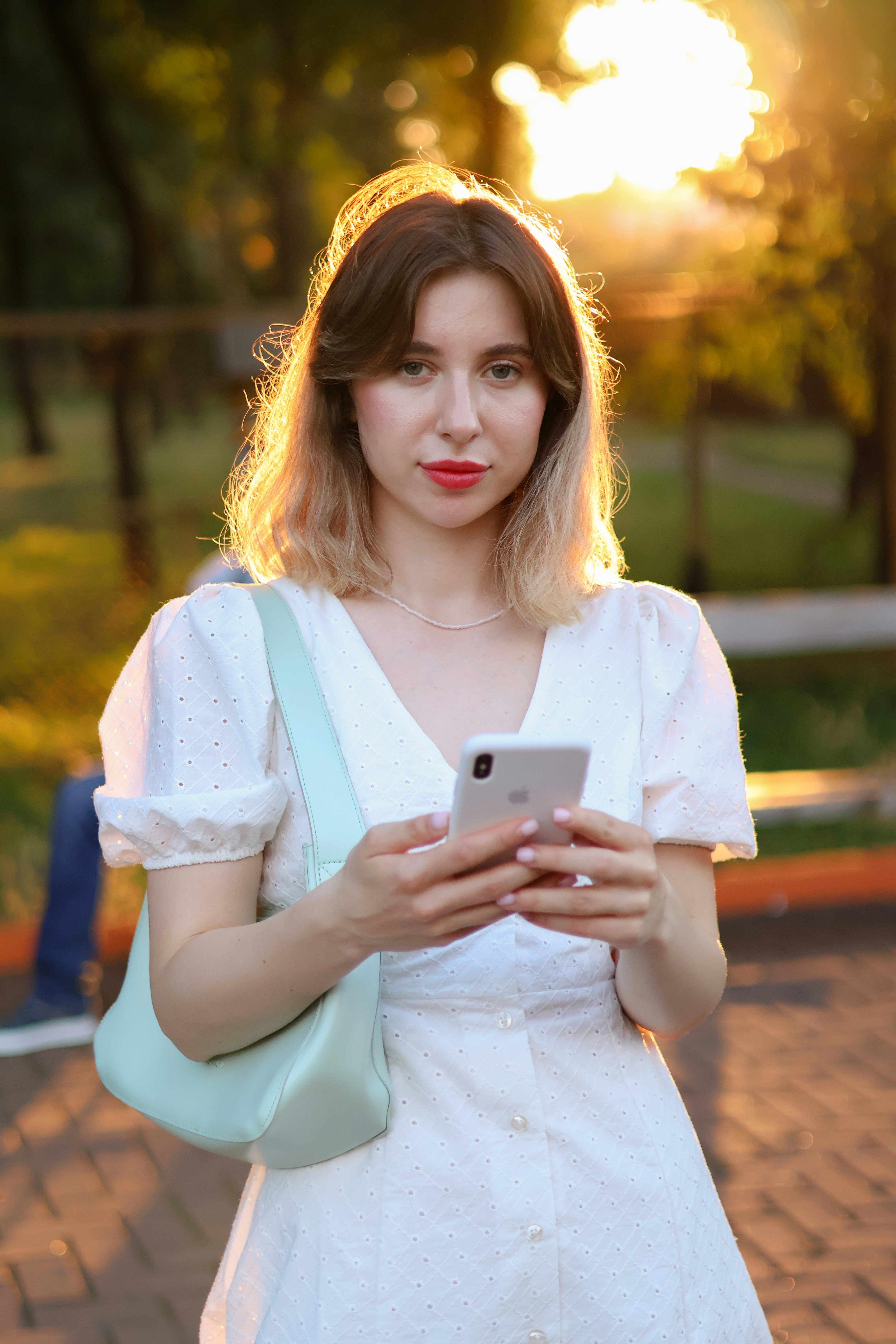 a woman in a white dress holding a cell phone
