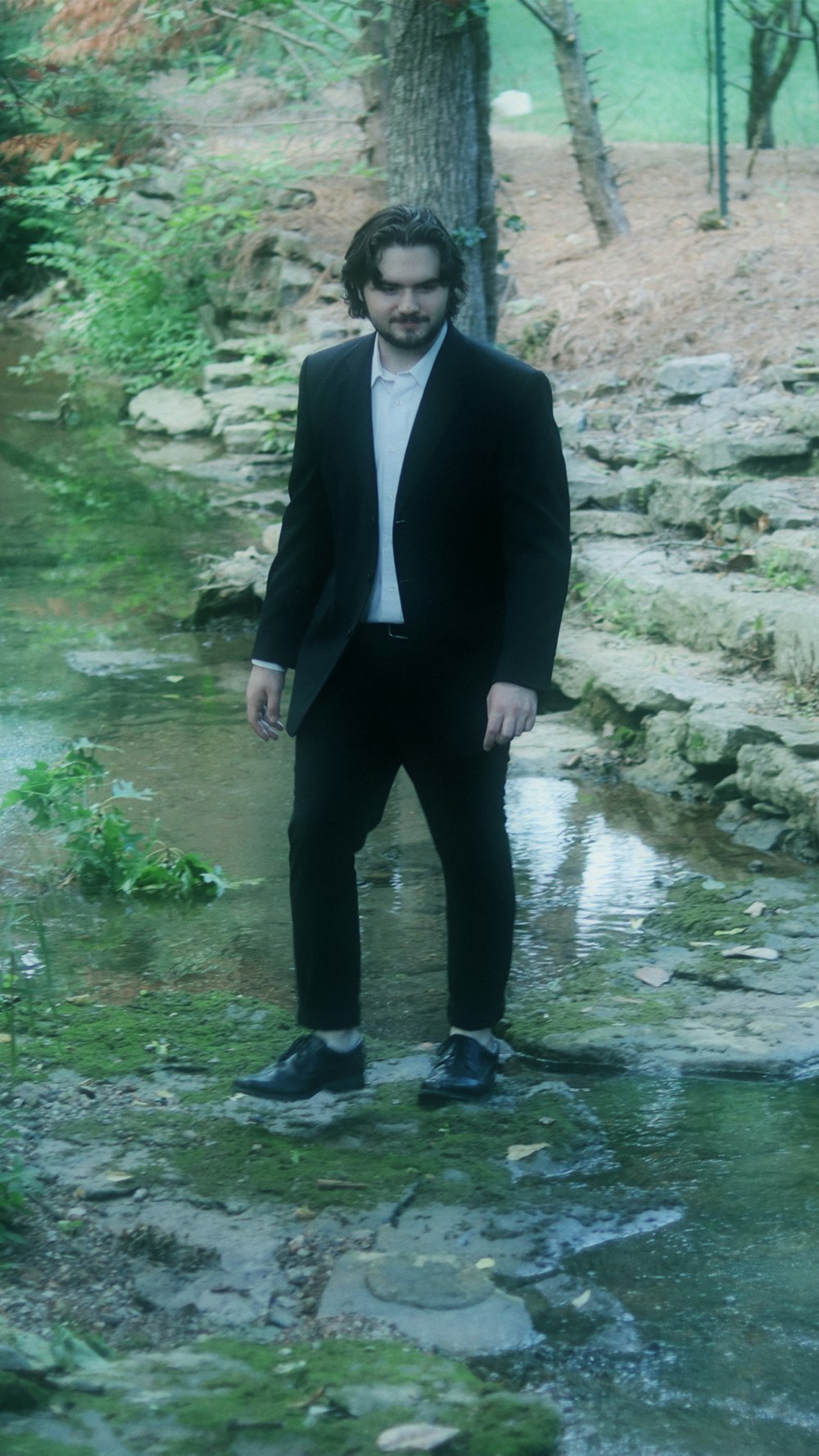 a man in a suit standing in a stream