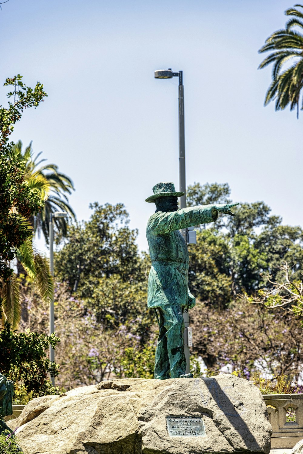 a statue of a man with a hat on top of a rock