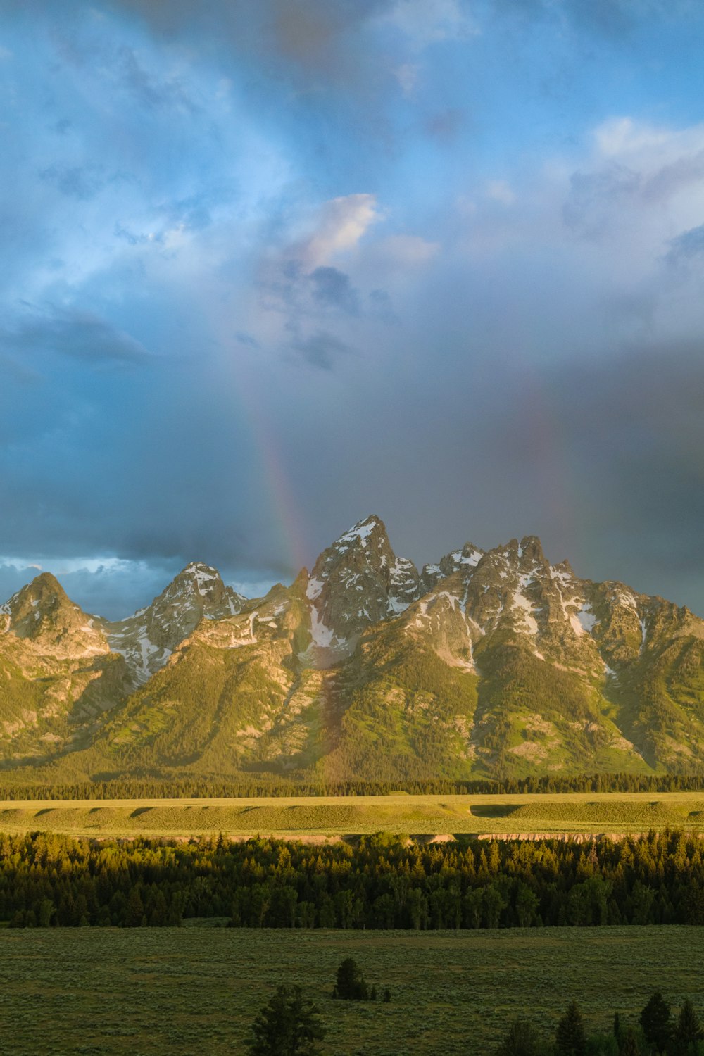 a rainbow in the sky over a mountain range