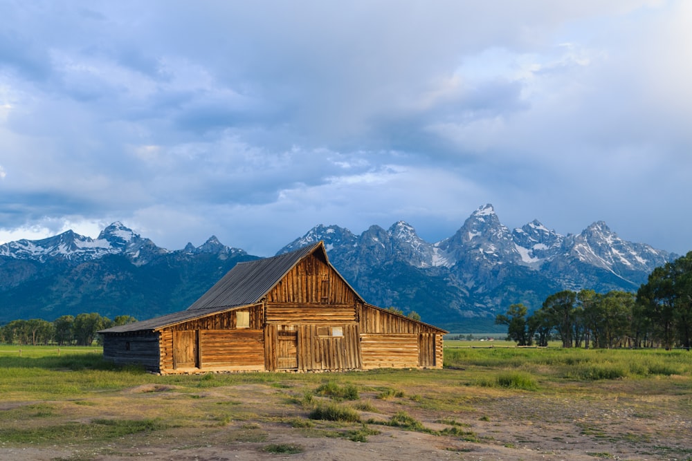 a barn in a field with mountains in the background