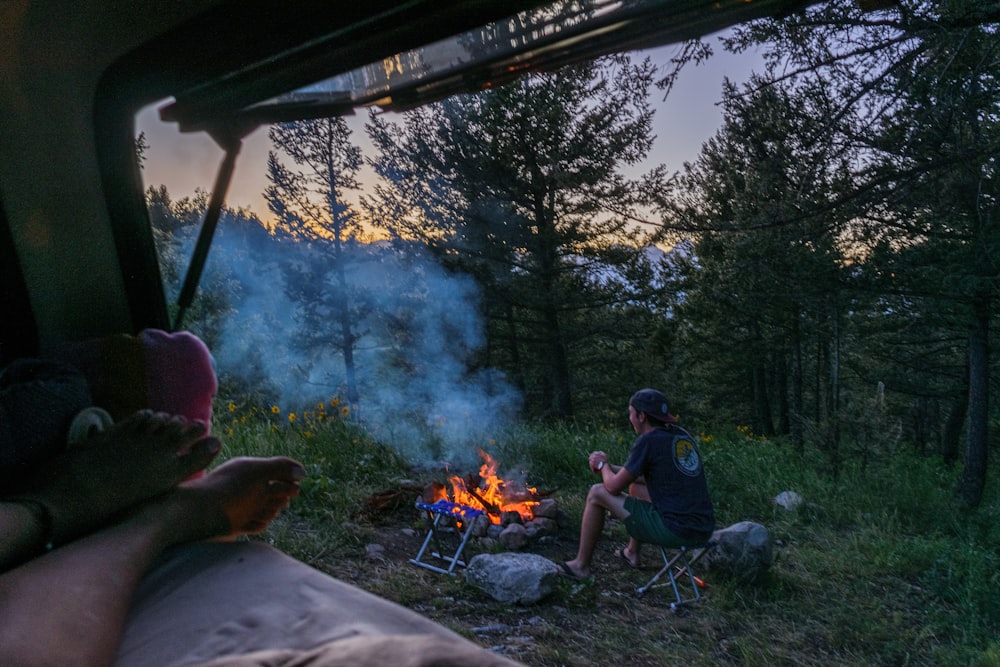 a man sitting in a chair next to a campfire