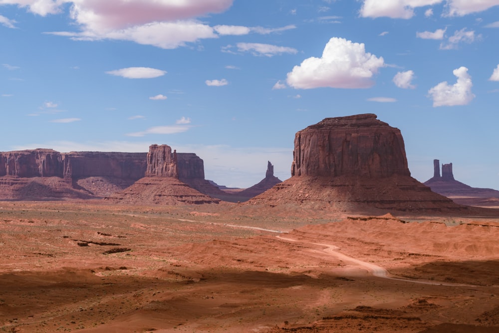 a desert landscape with mountains and clouds in the background