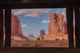 Close-up of two members shaking hands with the red sandstone landscape visible through a window.