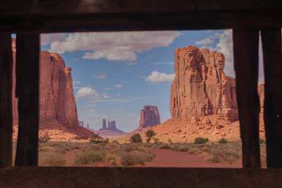 Close-up of two members shaking hands with the red sandstone landscape visible through a window.