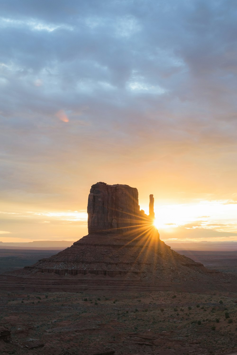 the sun is setting behind a large rock formation